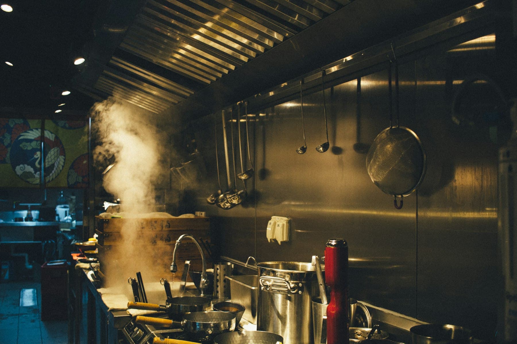 Steam rising from pots on a busy restaurant cooking line